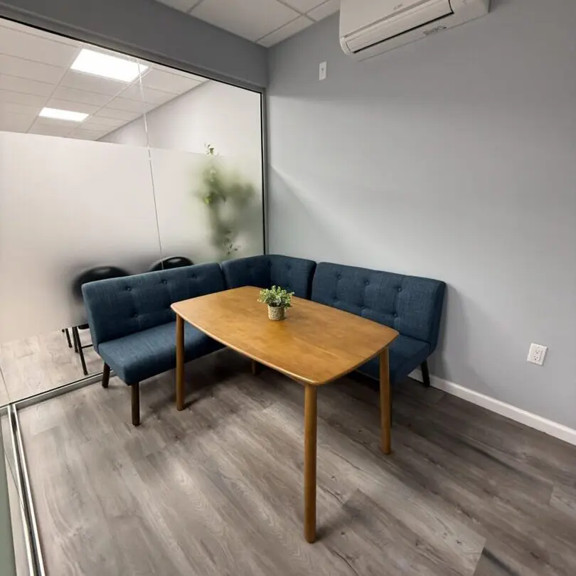 Cozy office seating area with blue sofas and a wooden table.